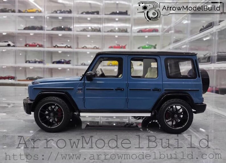 May include: A blue model SUV with black wheels and a spare tire on the back. The vehicle has a black roof and trim. The text "ArrowModelBuild" and a website address are visible at the bottom of the image.