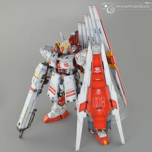 May include: A detailed model of a white and red mecha robot with intricate paneling and accents. The robot features a large backpack with white and red wings, and a long, cylindrical weapon. The model is labeled with the number "01".