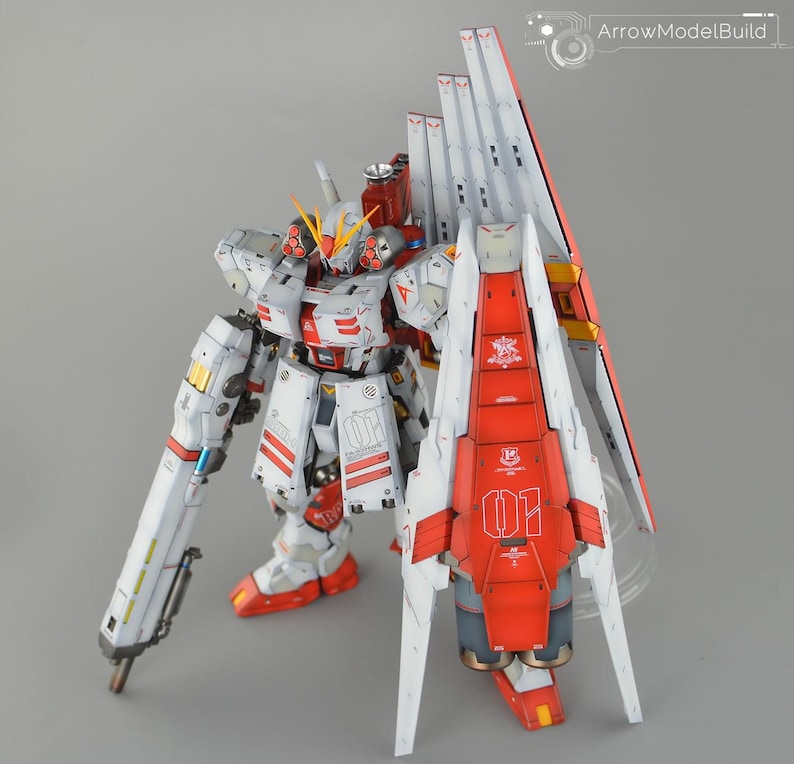 May include: A detailed model of a white and red mecha robot with intricate paneling and accents. The robot features a large backpack with white and red wings, and a long, cylindrical weapon. The model is labeled with the number "01".