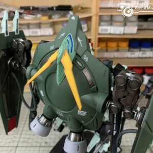 Puede incluir: Un detallado kit de modelo verde oliva de un robot mec&aacute;nico con detalles amarillos y azules. El modelo presenta intrincados detalles mec&aacute;nicos, incluyendo escudos, propulsores y articulaciones. El kit est&aacute; parcialmente montado.