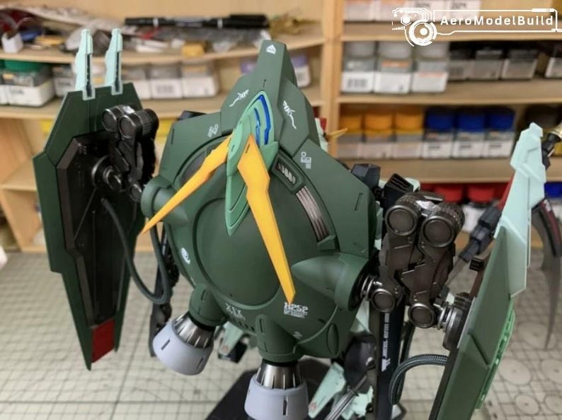 Puede incluir: Un detallado kit de modelo verde oliva de un robot mec&aacute;nico con detalles amarillos y azules. El modelo presenta intrincados detalles mec&aacute;nicos, incluyendo escudos, propulsores y articulaciones. El kit est&aacute; parcialmente montado.