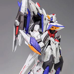 Puede incluir: Maqueta detallada de un robot futurista, principalmente blanco con detalles azules, rojos y naranjas. El modelo presenta paneles intrincados y &aacute;ngulos agudos, con una gran estructura en forma de ala en la espalda. El logotipo de AeroModelBuild es visible.