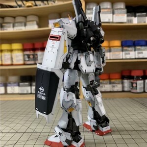 Pode incluir: Modelo detalhado de um rob&ocirc; branco, preto e cinza com detalhes em vermelho. O rob&ocirc; tem um escudo com o texto "A.E.U.G. AC004" e est&aacute; posicionado sobre uma superf&iacute;cie quadriculada. Provavelmente &eacute; um item de colecionador ou um projeto de hobby.