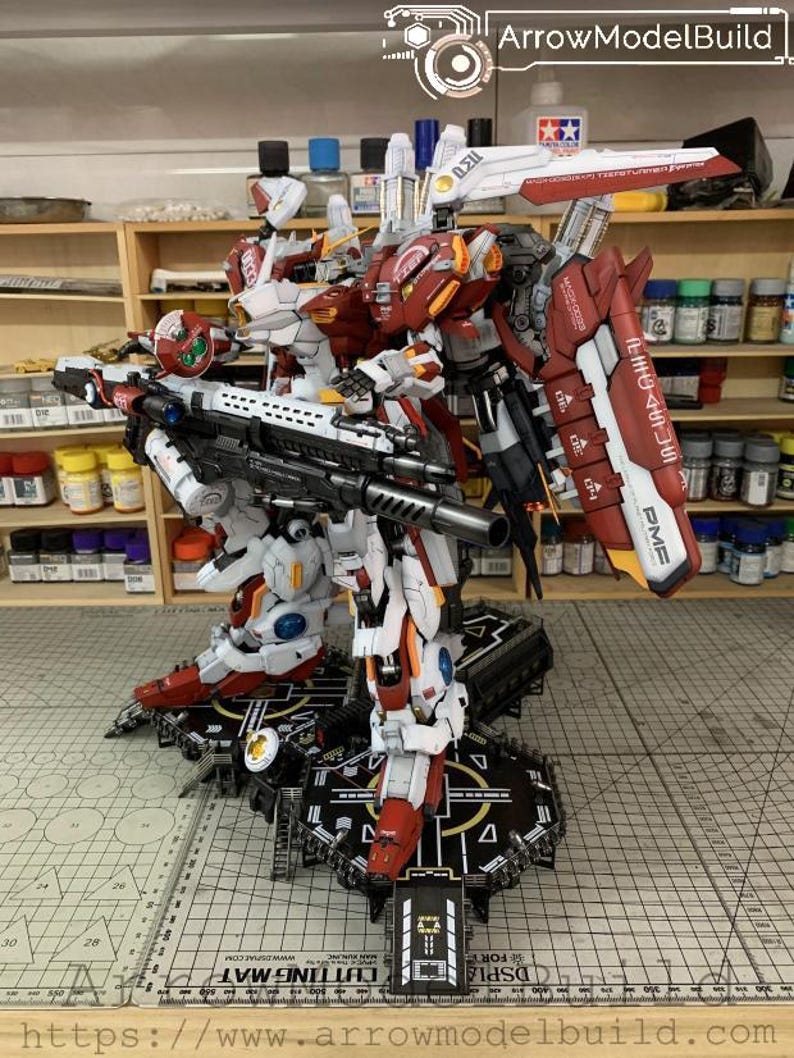 Puede incluir: Un modelo detallado de un robot mecha, principalmente blanco y rojo, con detalles en negro y gris. El robot est&aacute; de pie sobre una plataforma negra con un dise&ntilde;o complejo. La imagen incluye el texto "ArrowModelBuild" y "DSPLA".