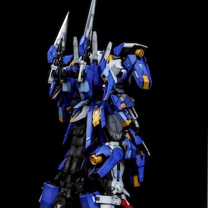 May include: A detailed model of a blue and white mecha robot with yellow accents and sharp, blade-like weapons. The model is posed against a black background, showcasing its intricate design and construction. The text "AeroModelBuild" is visible.