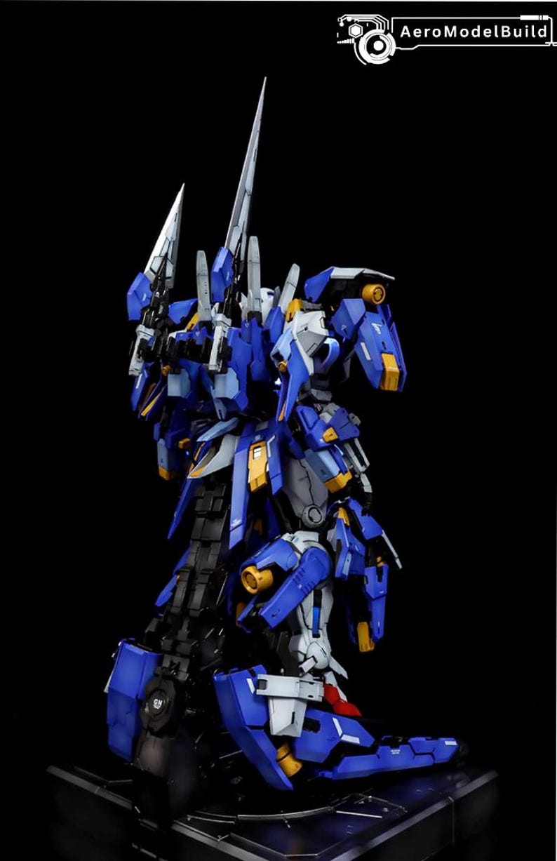 May include: A detailed model of a blue and white mecha robot with yellow accents and sharp, blade-like weapons. The model is posed against a black background, showcasing its intricate design and construction. The text "AeroModelBuild" is visible.