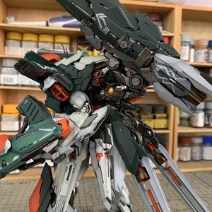 May include: A detailed model of a futuristic robot with a complex design. The robot features a color scheme of dark green, white, orange, and silver. The model is highly detailed, with visible mechanical components and intricate paneling.