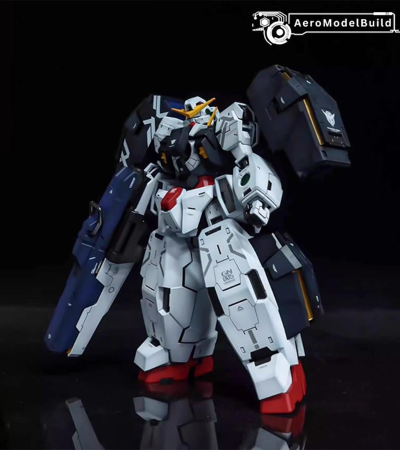 May include: A detailed model of a Gundam robot, primarily white with blue, black, red, and yellow accents. The robot has a complex design with multiple panels and articulated parts, standing on a reflective surface.