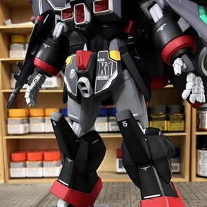 May include: A detailed model robot with a black, gray, and red color scheme. The model features intricate mechanical details, including panels, joints, and weapons. The text "GFAS-X1 DESTROY" is visible on the model. The model is posed in a standing position.