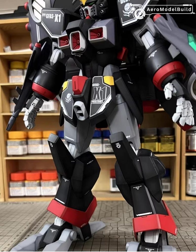 May include: A detailed model robot with a black, gray, and red color scheme. The model features intricate mechanical details, including panels, joints, and weapons. The text "GFAS-X1 DESTROY" is visible on the model. The model is posed in a standing position.