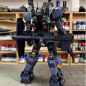 Pu&ograve; includere: Modello dettagliato di un robot mecha blu scuro e nero, con un grande fucile e pi&ugrave; propulsori. Il modello ha accenti arancioni e il numero "01" &egrave; visibile. Il logo AeroModelBuild &egrave; nell'angolo in alto a destra.