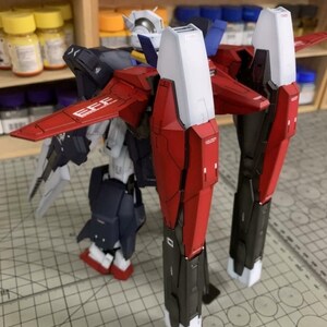Puede incluir: Modelo detallado de un robot mec&aacute;nico, con componentes rojos, blancos, negros y azul marino. El robot tiene grandes piezas de armadura angulares y alas. El texto "EFE" es visible en el ala roja.