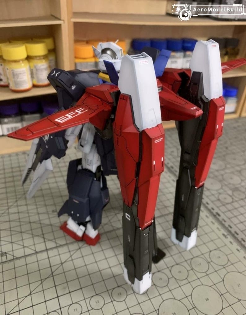 Puede incluir: Modelo detallado de un robot mec&aacute;nico, con componentes rojos, blancos, negros y azul marino. El robot tiene grandes piezas de armadura angulares y alas. El texto "EFE" es visible en el ala roja.