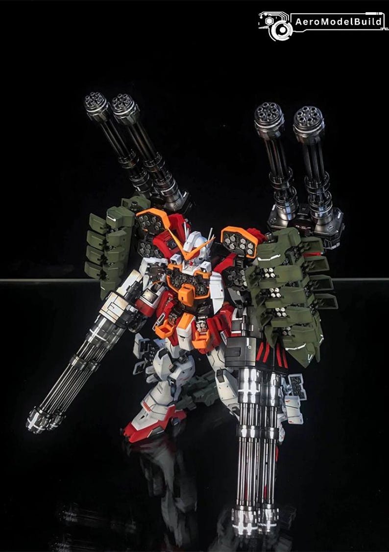 K&ouml;nnte beinhalten: Ein hochdetailliertes Gundam-Modell in Wei&szlig;, Rot und Orange mit olivgr&uuml;nen Raketenwerfern. Die Figur ist mit vier gro&szlig;en schwarzen Gatling-Kanonen ausgestattet, die an den Schultern montiert und in den H&auml;nden gehalten werden, vor einem schwarzen Hintergrund mit dem Text AeroModelBuild in der oberen rechten Ecke.