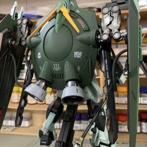 Puede incluir: Modelo detallado de un robot mec&aacute;nico verde y blanco con varios accesorios, incluyendo un escudo, una lanza y m&uacute;ltiples propulsores. El modelo tiene detalles intrincados y est&aacute; montado sobre un soporte negro. El logotipo de AeroModelBuild es visible en la esquina superior derecha.