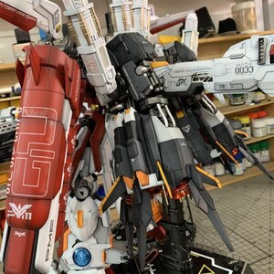 Puede incluir: Modelo detallado de un robot con detalles en rojo, blanco, negro y dorado. El modelo presenta intrincados detalles mec&aacute;nicos, incluyendo m&uacute;ltiples paneles, articulaciones y armas. El texto "ArrowModelBuild" es visible.