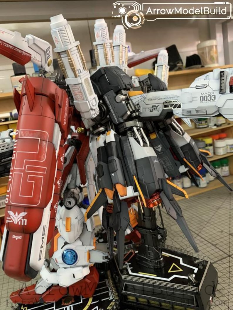 Puede incluir: Modelo detallado de un robot con detalles en rojo, blanco, negro y dorado. El modelo presenta intrincados detalles mec&aacute;nicos, incluyendo m&uacute;ltiples paneles, articulaciones y armas. El texto "ArrowModelBuild" es visible.