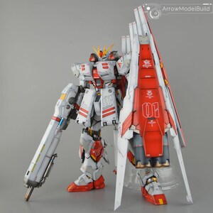 May include: A detailed model of a white and red mecha robot with a large shield. The robot has intricate paneling, red accents, and the number "01" is visible. The model is standing on a clear stand against a grey background.