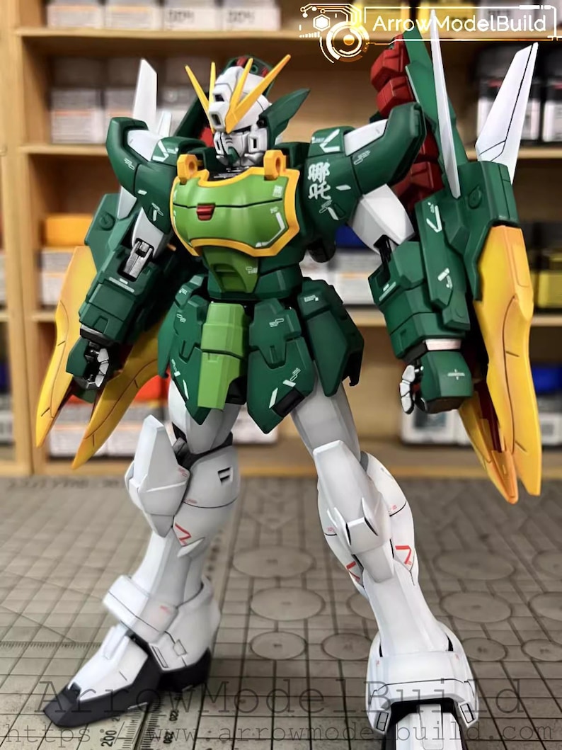 May include: A detailed model of a Gundam robot, predominantly green, white, and yellow. The robot has intricate armour plating, articulated joints, and a detailed head with yellow accents. The model is posed in a standing position, showcasing its design and construction.
