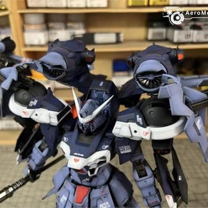 May include: A detailed model of a futuristic robot, primarily in shades of blue, gray, and white. The robot has intricate mechanical details, including wings, turbines, and a weapon. The model is set against a backdrop of shelves filled with various items.
