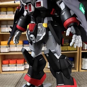 May include: A detailed model of a mecha robot, primarily black, gray, and red. The model features intricate paneling, articulated limbs, and the text "GFAS-K1" and "DESTROY". The robot has a shield and is set against a background of paint supplies.