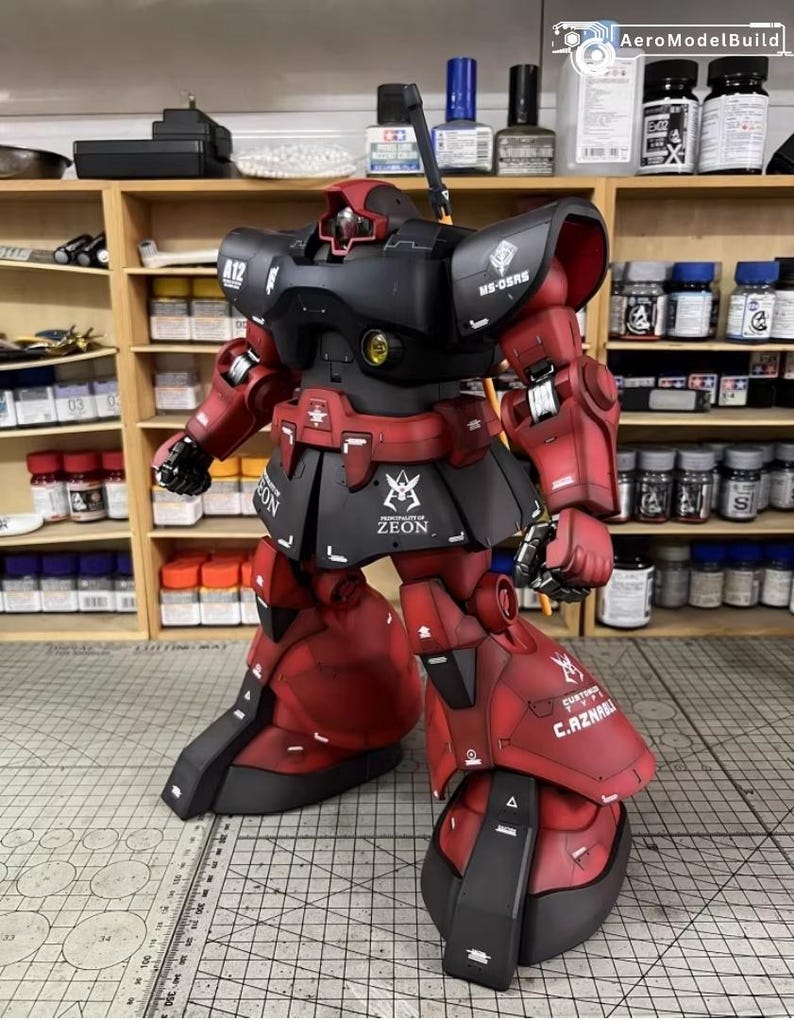 May include: A detailed model of a red and black robot with intricate detailing. The robot has a black head and torso, with red arms, legs, and feet. The model has the word "ZEON" printed on the skirt.