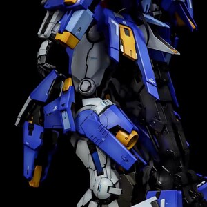 May include: A detailed, partially assembled model kit of a robot, featuring a color scheme of blue, white, gray, and yellow. The model has intricate mechanical details and is set against a black background. The text "AeroModelBuild" is visible.