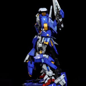 May include: A detailed model of a robot, primarily blue, white, and yellow, with a large blade. The model is standing on a black base. The text "AeroModelBuild" is in the upper right corner.