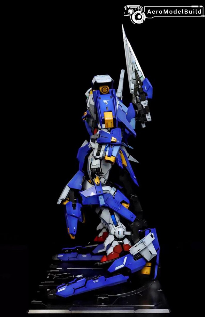 May include: A detailed model of a robot, primarily blue, white, and yellow, with a large blade. The model is standing on a black base. The text "AeroModelBuild" is in the upper right corner.