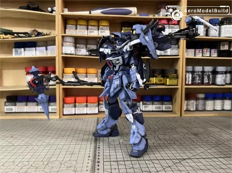 May include: A detailed model of a blue and gray mech robot, with intricate armor and weaponry. The model is posed on a grid surface, with shelves of paint and supplies in the background. AeroModelBuild logo is visible.