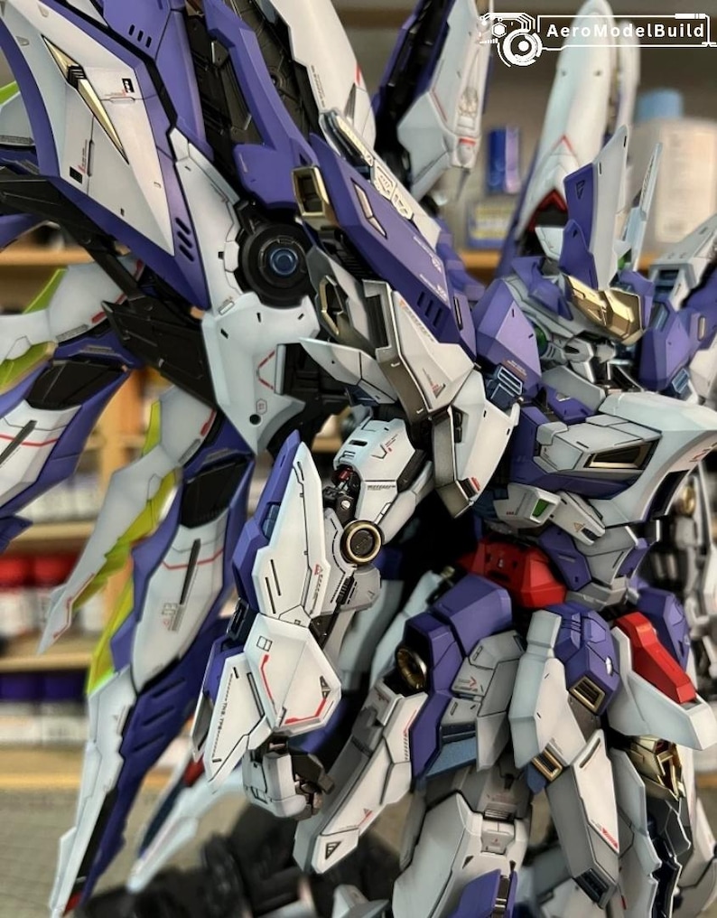 May include: A detailed model robot with a futuristic design, featuring white, purple, and gold accents. The model has intricate mechanical details, suggesting it is a collectible item or a hobby project.