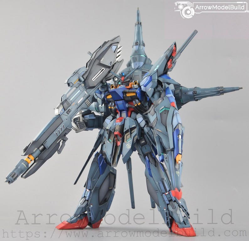 Puede incluir: Modelo detallado de un robot futurista, principalmente en tonos azules, grises y rojos. El robot tiene un arma grande en su lado izquierdo y m&uacute;ltiples estructuras puntiagudas. El texto "ArrowModelBuild" es visible en la esquina superior derecha e inferior.