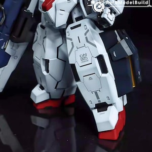 May include: Close-up of a white and gray model robot with red accents on the feet. The robot has detailed panel lines and the text "GN 005" is visible on the leg armor. The model is a detailed representation of a mecha.