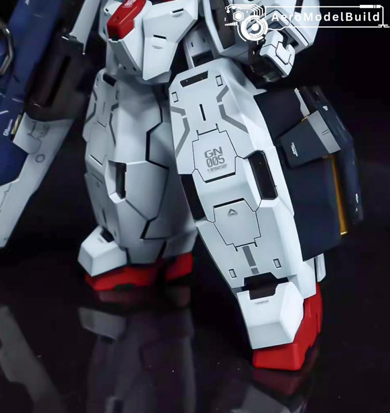May include: Close-up of a white and gray model robot with red accents on the feet. The robot has detailed panel lines and the text "GN 005" is visible on the leg armor. The model is a detailed representation of a mecha.