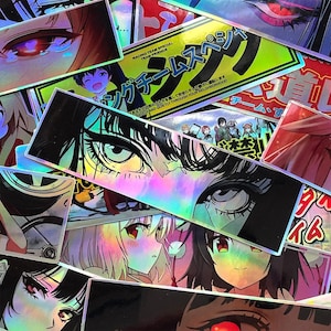 Puede incluir: Una colección de pegatinas holográficas rectangulares con diversas ilustraciones de estilo anime, incluyendo primeros planos de ojos, personajes con cabello de colores y texto en japonés. Las pegatinas tienen un acabado reflectante.