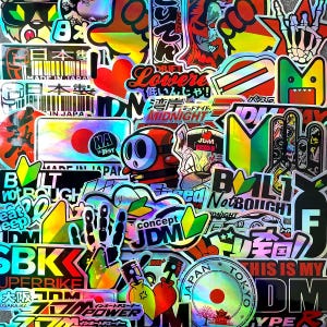 Puede incluir: Una colección de pegatinas holográficas con varios diseños y texto. Las pegatinas presentan texto japonés, personajes de dibujos animados y gráficos de temática automovilística. Los colores incluyen rojo, verde, azul y amarillo.