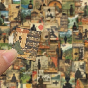 May include: A small, rectangular, vintage-style image featuring a seated figure in green robes, reading. The background is a collection of similar images with various Japanese-inspired scenes and figures. The image is held in a person's hand.