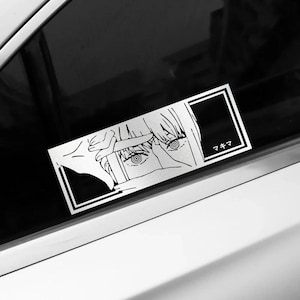 Puede incluir: Una calcomanía rectangular de vinilo blanco aplicada en la ventana de un coche, con una ilustración de líneas negras de un personaje con ojos anillados enmarcando su rostro con las manos y el texto japonés マキマ en un recuadro negro.