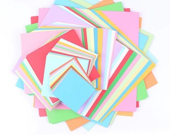 May include: A collection of colourful origami paper in various sizes and shades, including pink, blue, green, orange, and red. Some sheets have striped patterns in multiple colours. The paper is arranged in a circular shape.