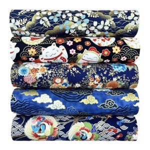 May include: A stack of five rolled fabric bolts with Japanese-inspired patterns. The fabrics feature navy, blue, and white backgrounds with floral, cloud, and lucky cat motifs. The fabrics are suitable for sewing and crafting projects.