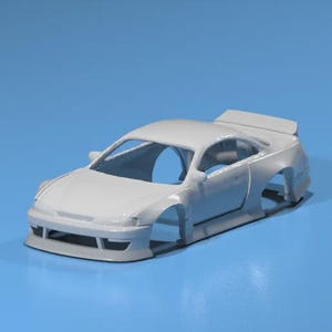 Puede incluir: Carrocería de coche modelo blanca, sin pintar, con alerón y guardabarros anchos. El coche tiene un interior abierto y está sobre una superficie azul. Ideal para personalización.