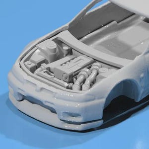 May include: A light gray model car with the hood open, revealing the engine. The engine components are detailed, including the intake manifold, exhaust pipes, and other mechanical parts. The car's body is visible, with the front bumper and part of the side.