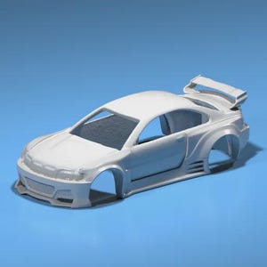 May include: A white model car with a spoiler, side skirts, and a front bumper. The car is missing wheels and sits on a blue surface. The car's body is a solid white color.
