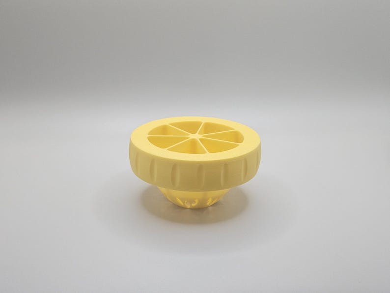 Op de afbeelding: Een gele citruspers met een gesegmenteerde bovenkant en een geribbelde basis. Deze pers is gemaakt van plastic en is ontworpen om sap uit citroenen en andere citrusvruchten te persen. Het ontwerp is eenvoudig en functioneel.