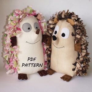 May include: Two plush hedgehog toys, one with pink and green fabric and the other with brown fabric. Both have white faces with black eyes and brown noses. The text "PDF PATTERN" is printed on the white hedgehog.