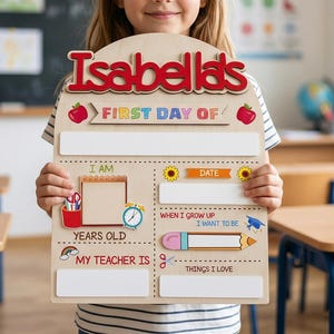 Op de afbeelding: Een houten bord met de naam "Isabella's" in rode letters. Het bord is voor de "Eerste schooldag" en heeft vakken om informatie over het kind in te vullen. Het bord bevat illustraties van appels, potloden en een klok.