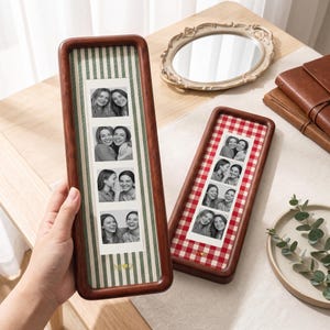 May include: Two tall, rectangular wooden photo frames with rounded corners. One frame features a green and white striped background with the letters M and Z separated by a heart. The other has a red and white gingham background with the letters N and Z separated by a heart. Each frame holds a vertical strip of four black and white photos showing two people smiling.