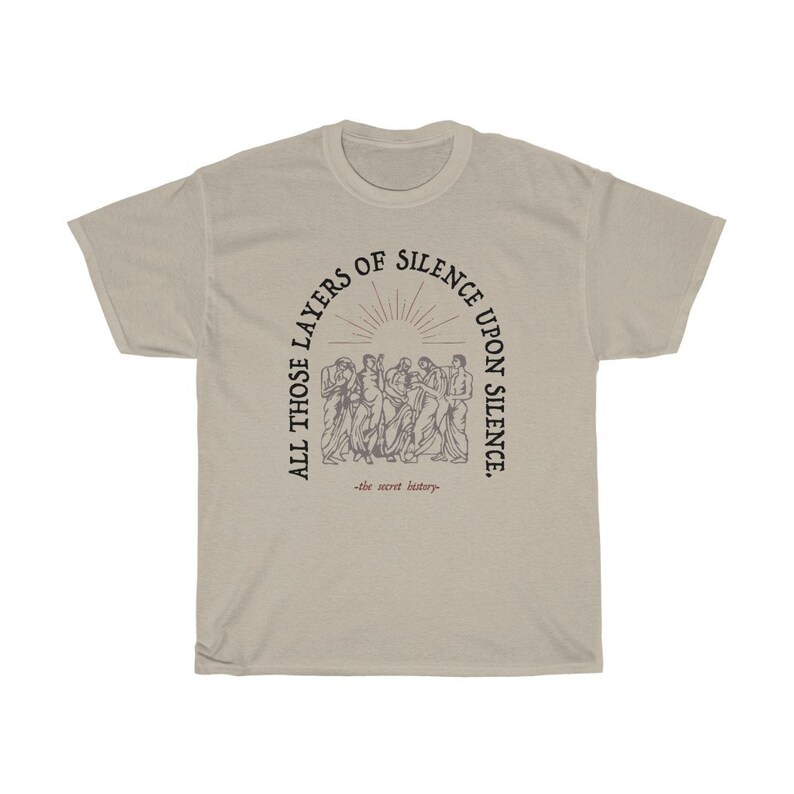May include: A beige t-shirt with a black graphic print of a group of people standing in a circle. The text around the graphic reads "All those layers of silence upon silence -the secret history-."
