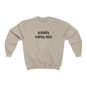 Puede incluir: Sudadera beige con mangas largas. El texto "probably reading smut" est&aacute; impreso en negro, con una fuente de estilo g&oacute;tico en el pecho. La sudadera est&aacute; hecha de un material suave.