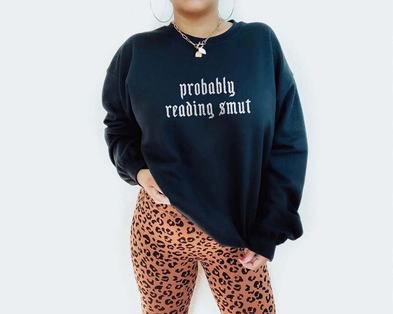 Puede incluir: Sudadera negra con la frase "probably reading smut" en fuente g&oacute;tica. Se combina con leggings con estampado de leopardo. El conjunto transmite un ambiente relajado y c&oacute;modo.
